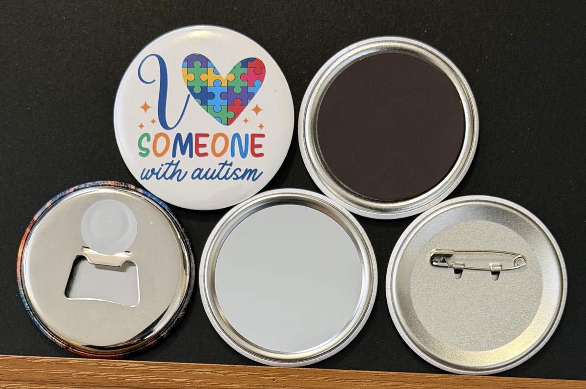 A white round button with 'I love someone with autism in multi-colored text, with yellow stars
and a multi-colored puzzle piece heart on a white background.  the other 4 buttons show the backside options which include magnet magnetic bottle cap opener, pin back button and pocket mirror.  Photographed on a black background.