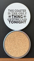 White round drink coaster with a cork backing with black decorative accents with text 'this coaster is the only thing getting laid tonight' on a white background.  This photo was taken on a black background.