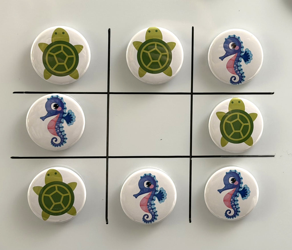 8 Tic Tac Toe small round magnets on a white background with a black grid pattern.  4 game pieces have  green turtle images and the other 4 images are pink and purple seahorses.