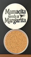 Round white drink coaster with cork backing with 'Mamacita needs a margarita' in black text, with an image of a black margarita glass, photographed on a black background.