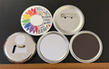 Round white magnet with a half image of a rainbow colored flower/petals with various pride-relates messages on the other side in black text with small multi-colored hearts and stars.  Also in the photo are the four options available for this magnet which include a pin back button, pocket mirror, magnetic bottle opener and magnet.  This photo was photographed on a black background.