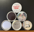 Set of personalized buttons with different designs featuring the backs of the buttons which include a magnet, pocket mirror, pin button and a magnetic bottle cap opener, on a black background