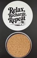 White round drink coaster with a cork backing with a black image of a palm tree and text 'relax, recharge, repeat' on a white background.  This photo was taken on a black background. 
