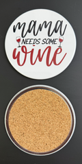 Round white drink coaster with cork backing with 'Mama Needs some wine' in red and black text, photographed on a black background.