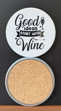 White round drink coaster with a cork backing with a black image of a WINE GLASS AND ARROW with text 'good ideas start with wine' on a white background.  This photo was taken on a black background.
